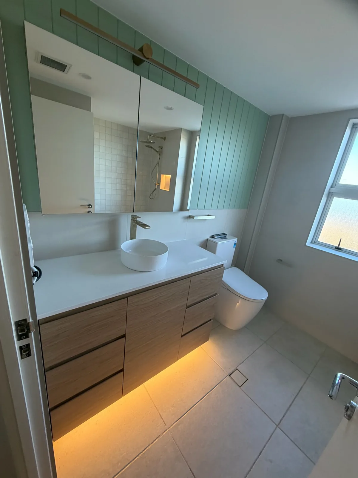 Custom timber vanity with a stone benchtop, round basin and mirrored shaving cabinet