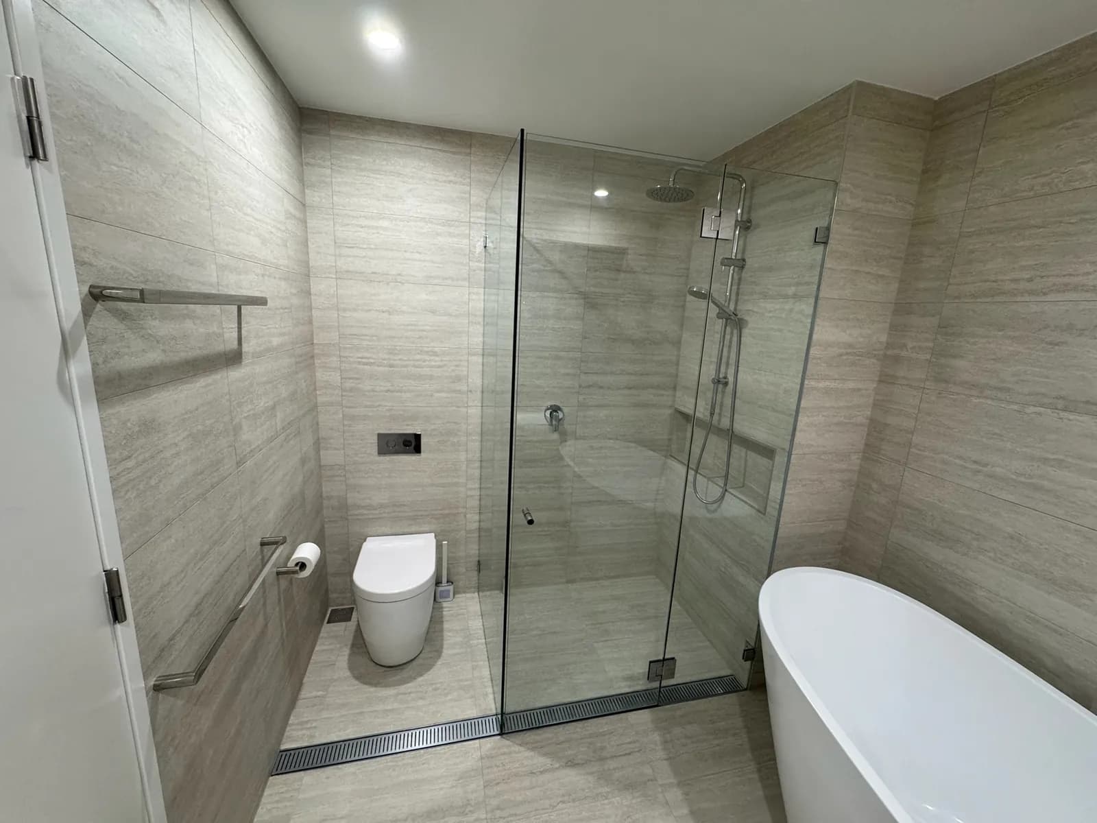 Bathroom with a frameless glass shower screen, linear floor waste and wall-hung toilet