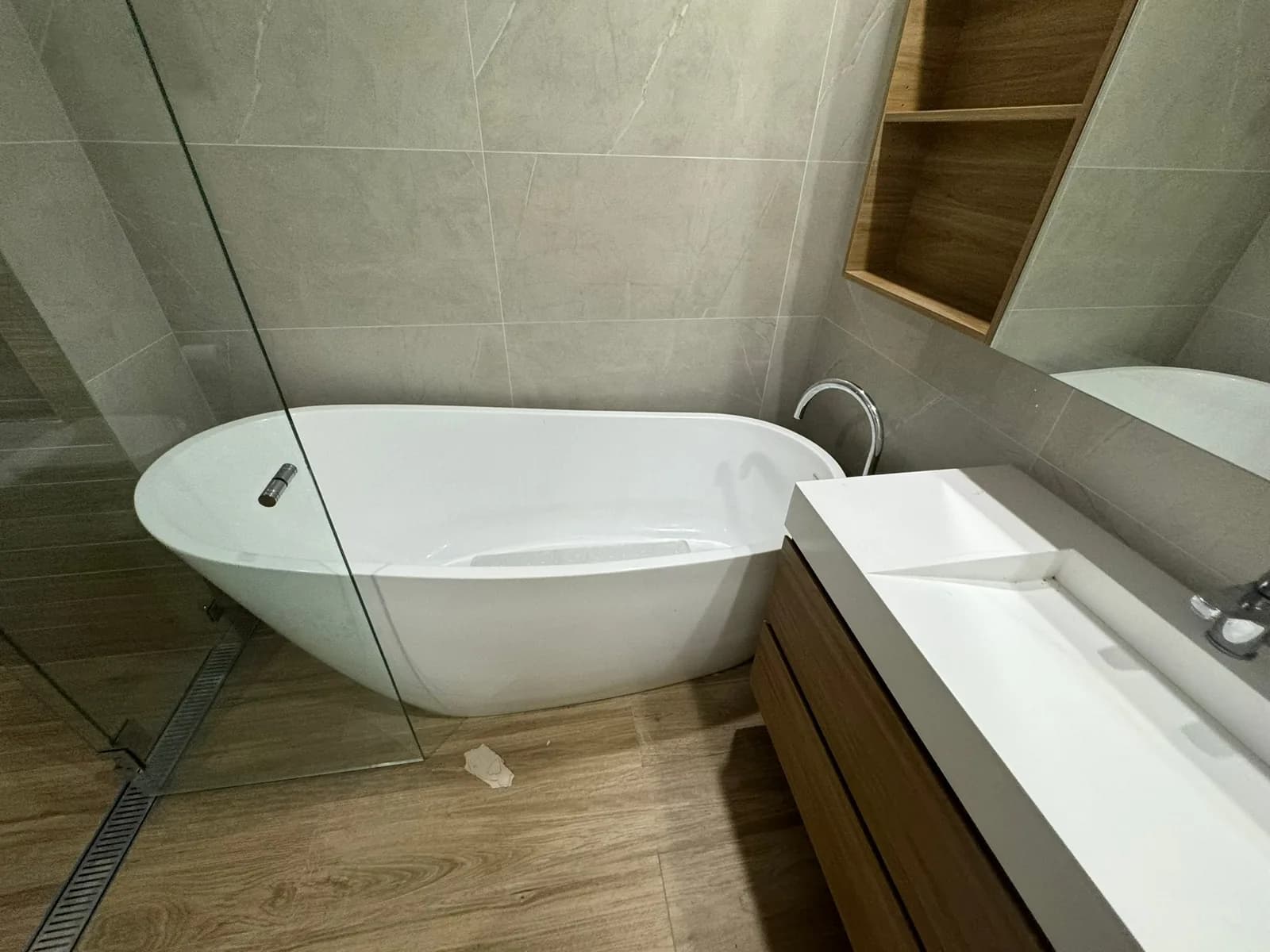 Freestanding bath against large-format stone-look tiling with a timber-look tiled floor