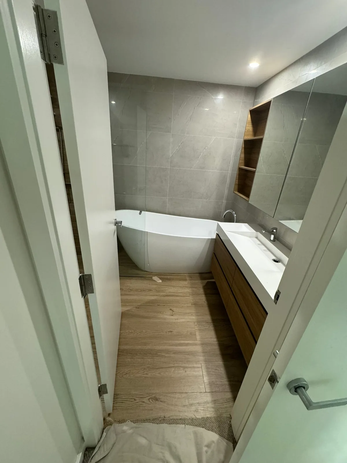 Bathroom with a freestanding bath, timber-look floor tiles and a full-height mirror