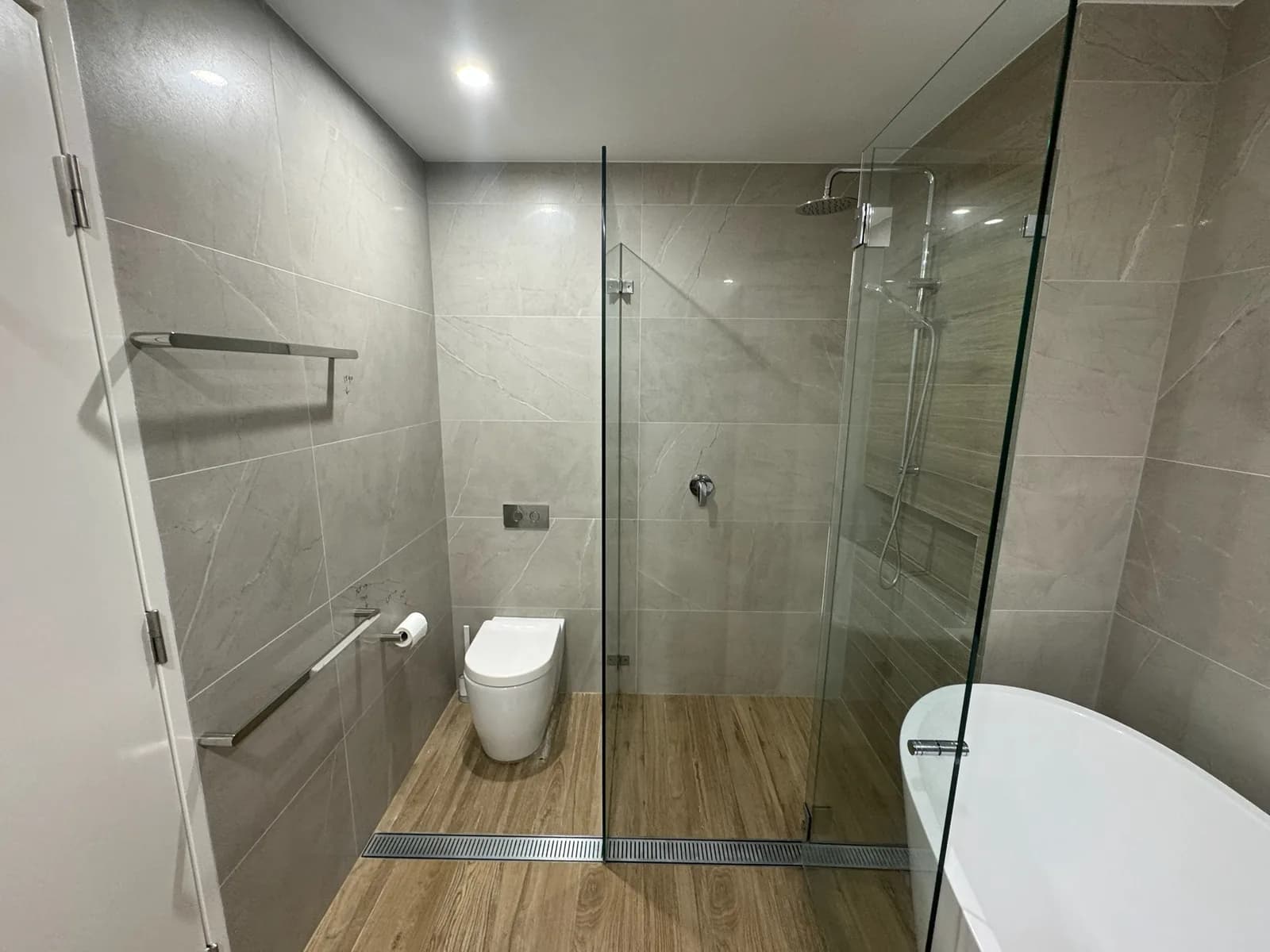 Glass shower enclosure with a linear drain set into timber-look floor tiles
