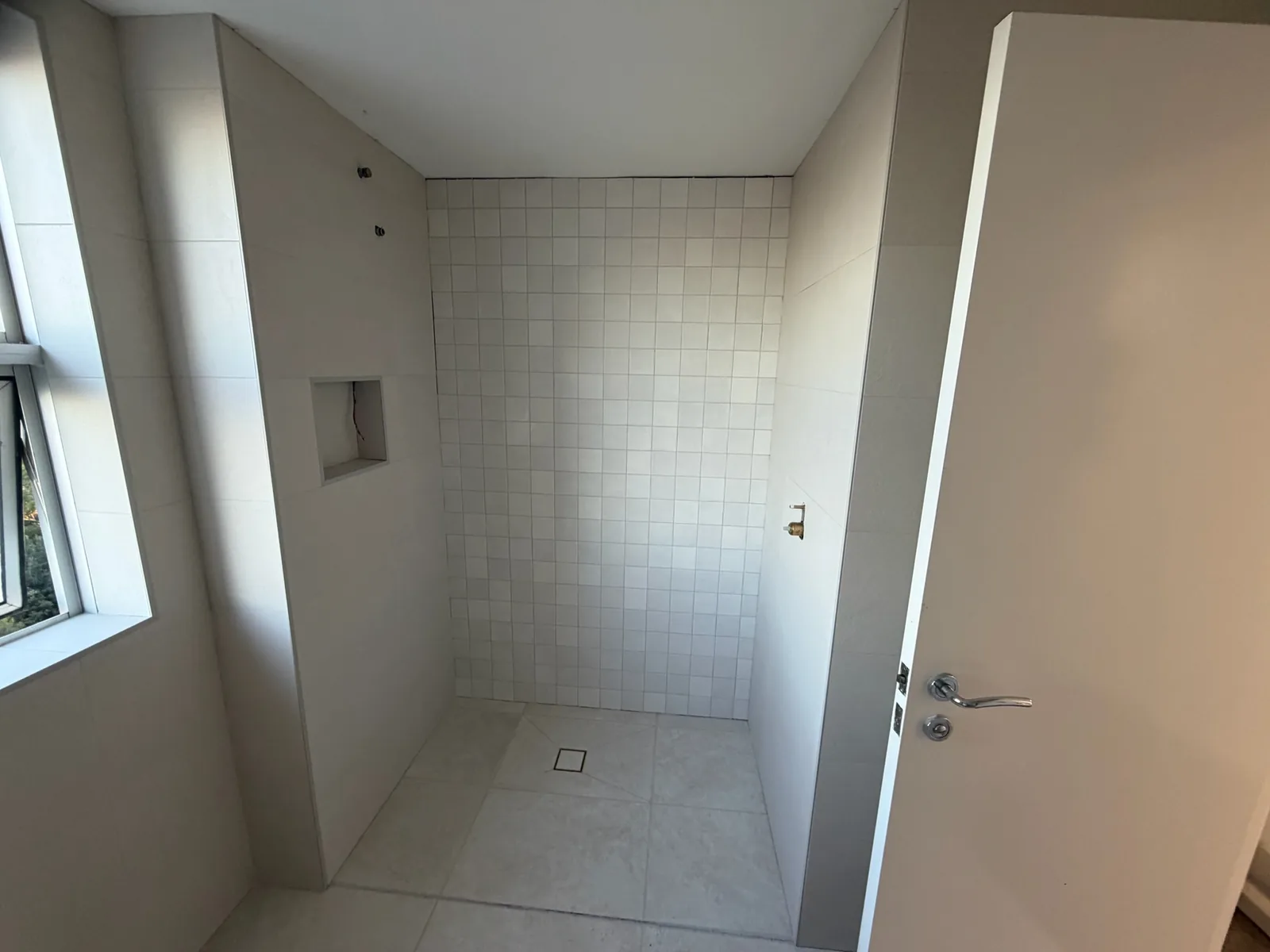 Walk-in shower tiled floor to ceiling with a recessed niche and step-free entry