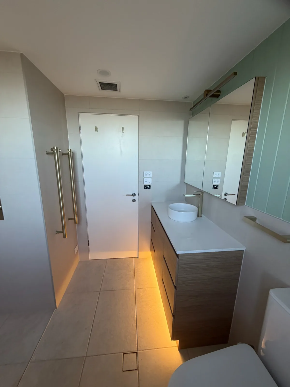 View across a finished bathroom from the vanity toward the shower and doorway