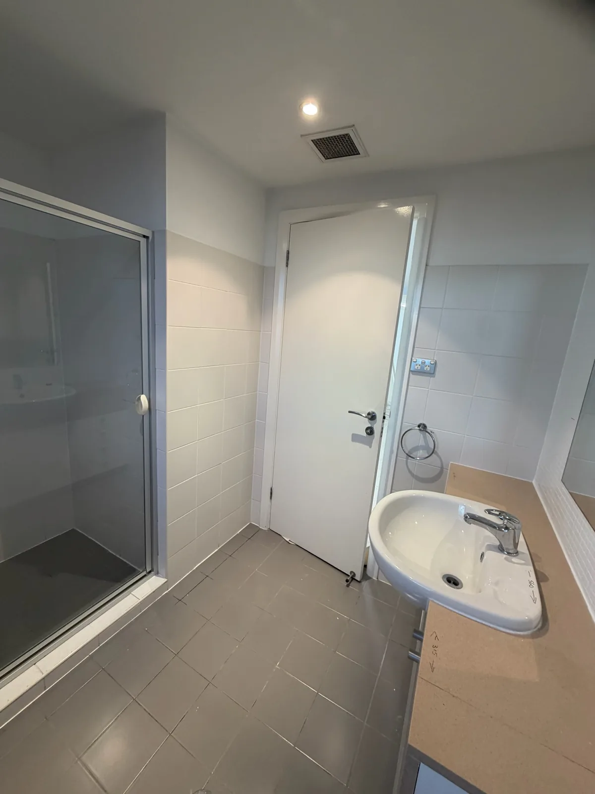 Original ensuite before renovation, with a framed shower screen and corner basin