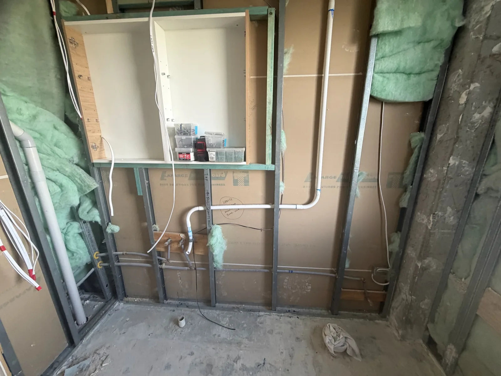 Steel stud wall framing with insulation, a built-in cabinet recess and plumbing rough-in