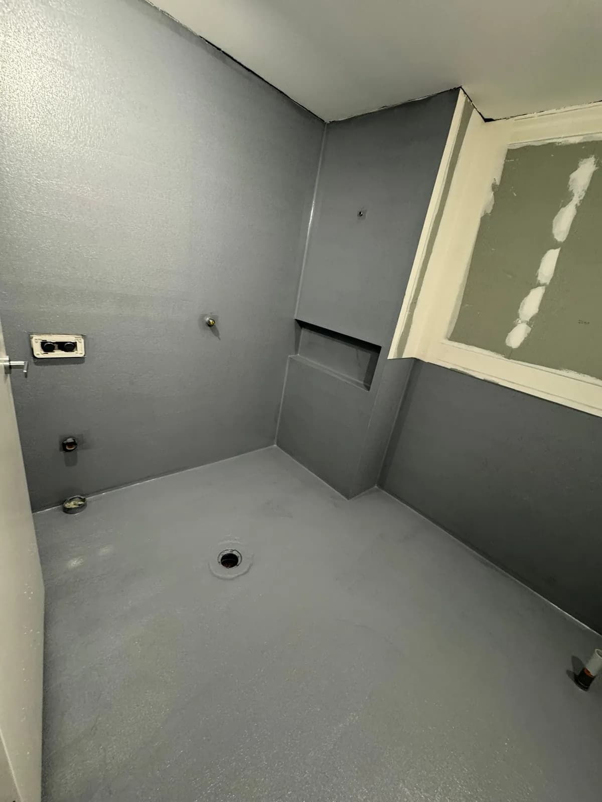 Waterproofing membrane over a shower hob and floor, ready for tiling